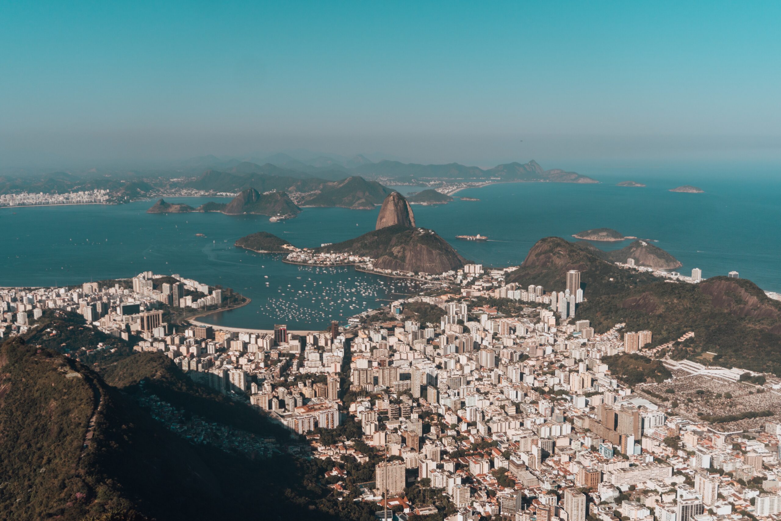 An aerial photo of Rio de Janeiro surrounded by hills and the sea under a blue sky in Brazil